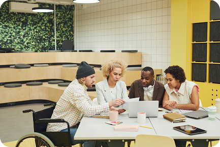 Divers team werkt samen aan een laptop in een inclusieve werkomgeving.