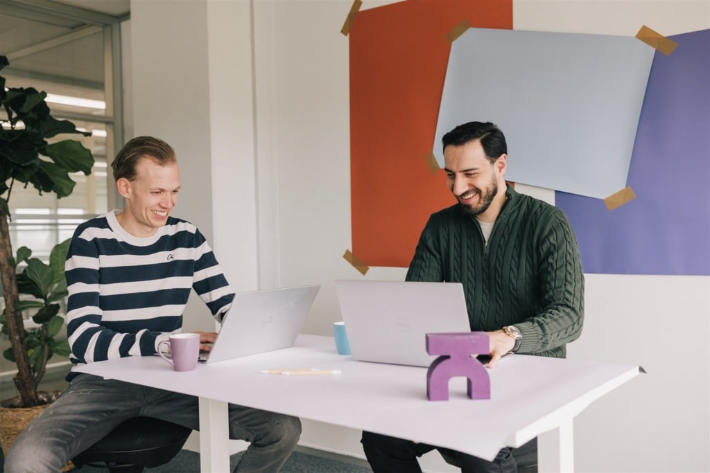 Two men watching a laptop, smiling